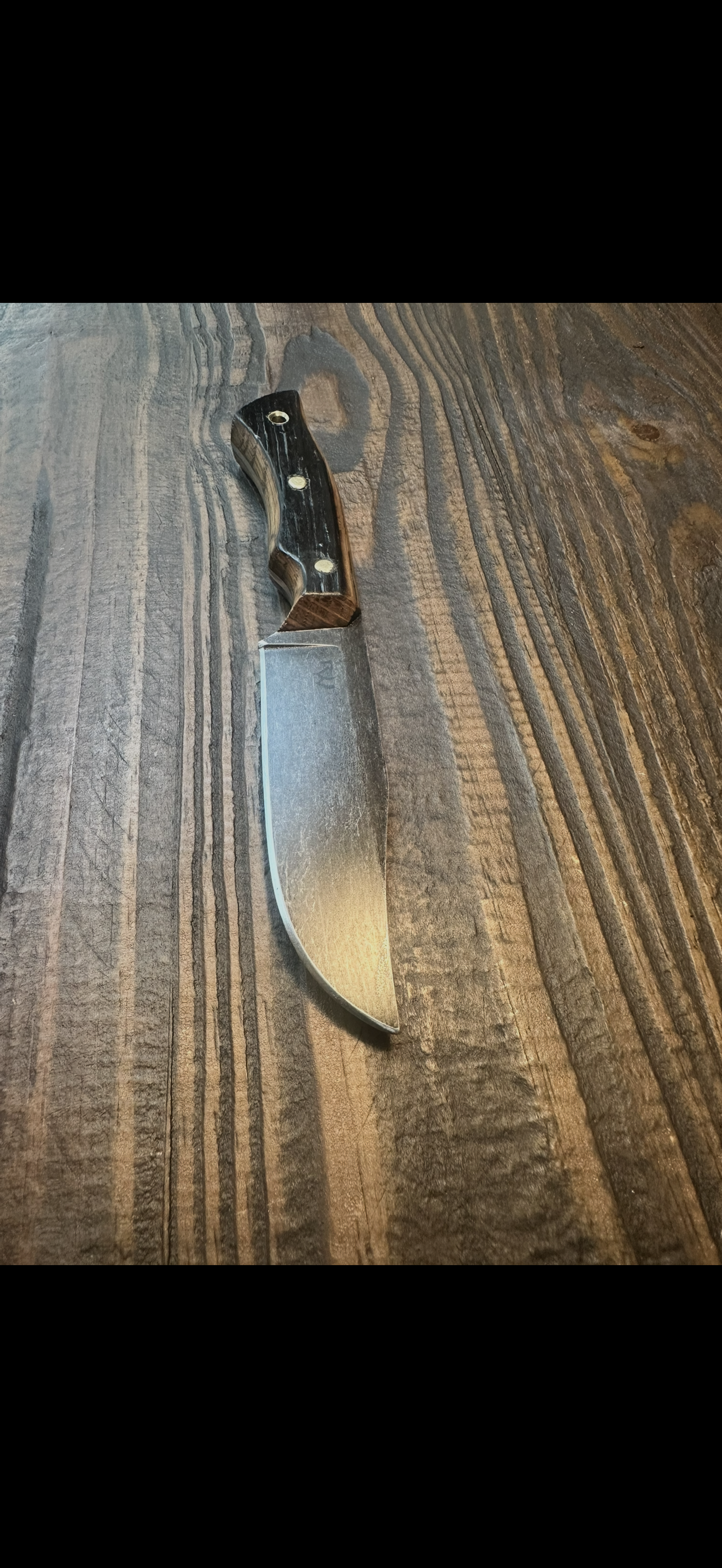 Hunter knife with dark handle on wood surface