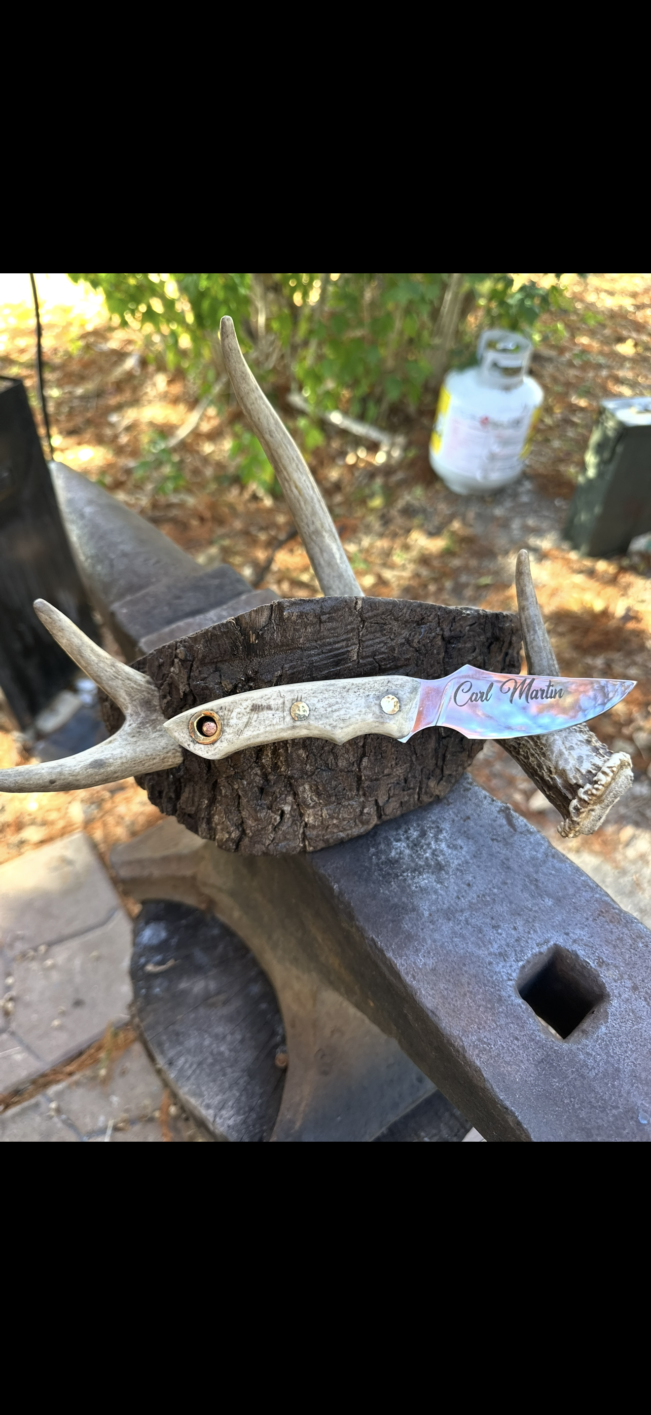 Custom engraved knife with antler handle on anvil